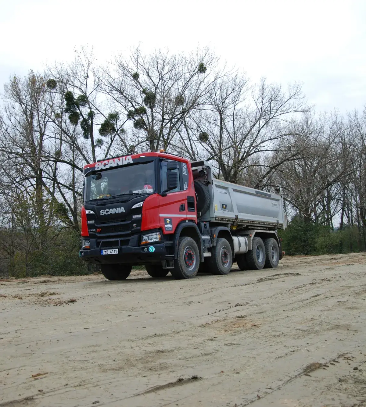 Sklápěč Scania 8x8 v barvách firmy na stavbě